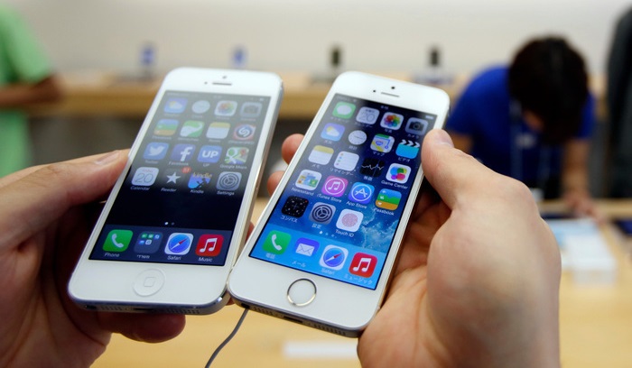 A man holds a new Apple iPhone 5S (R) next to his iPhone 5 at an Apple Store at Tokyo's Ginza shopping district September 20, 2013. REUTERS/Toru Hanai (JAPAN - Tags: BUSINESS TELECOMS) - RTX13RW2